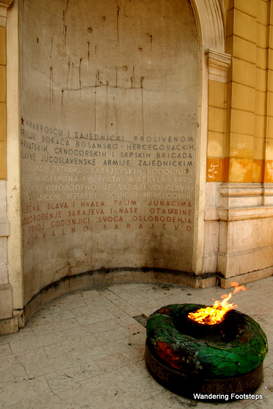 The Eternal Flame Monument, relit but still rippled with bullet holes.