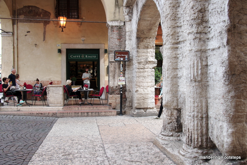 Porta Borsari, a Roman gate stuffed between modern buildings.