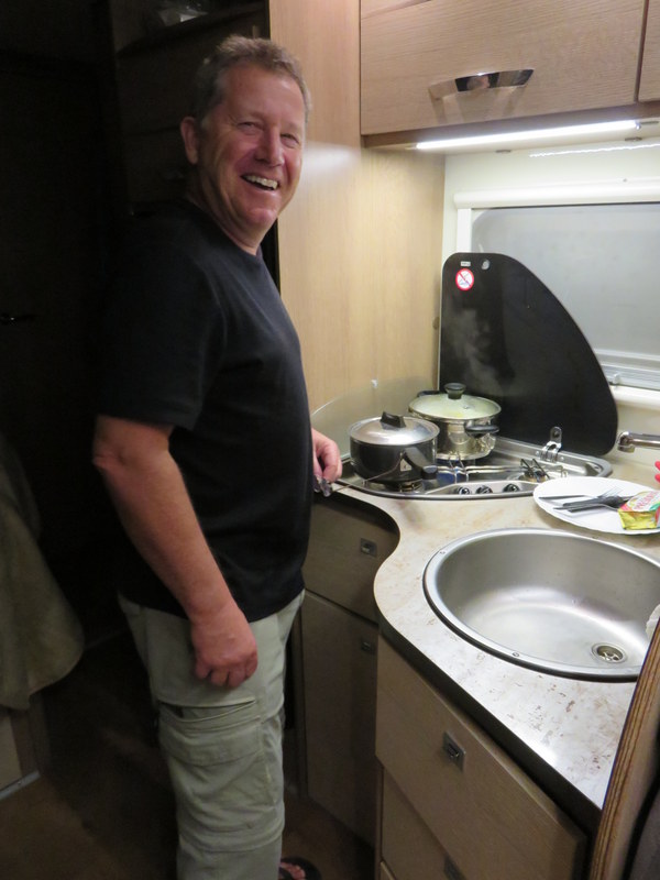 Dad cooking dinner inside their camper.